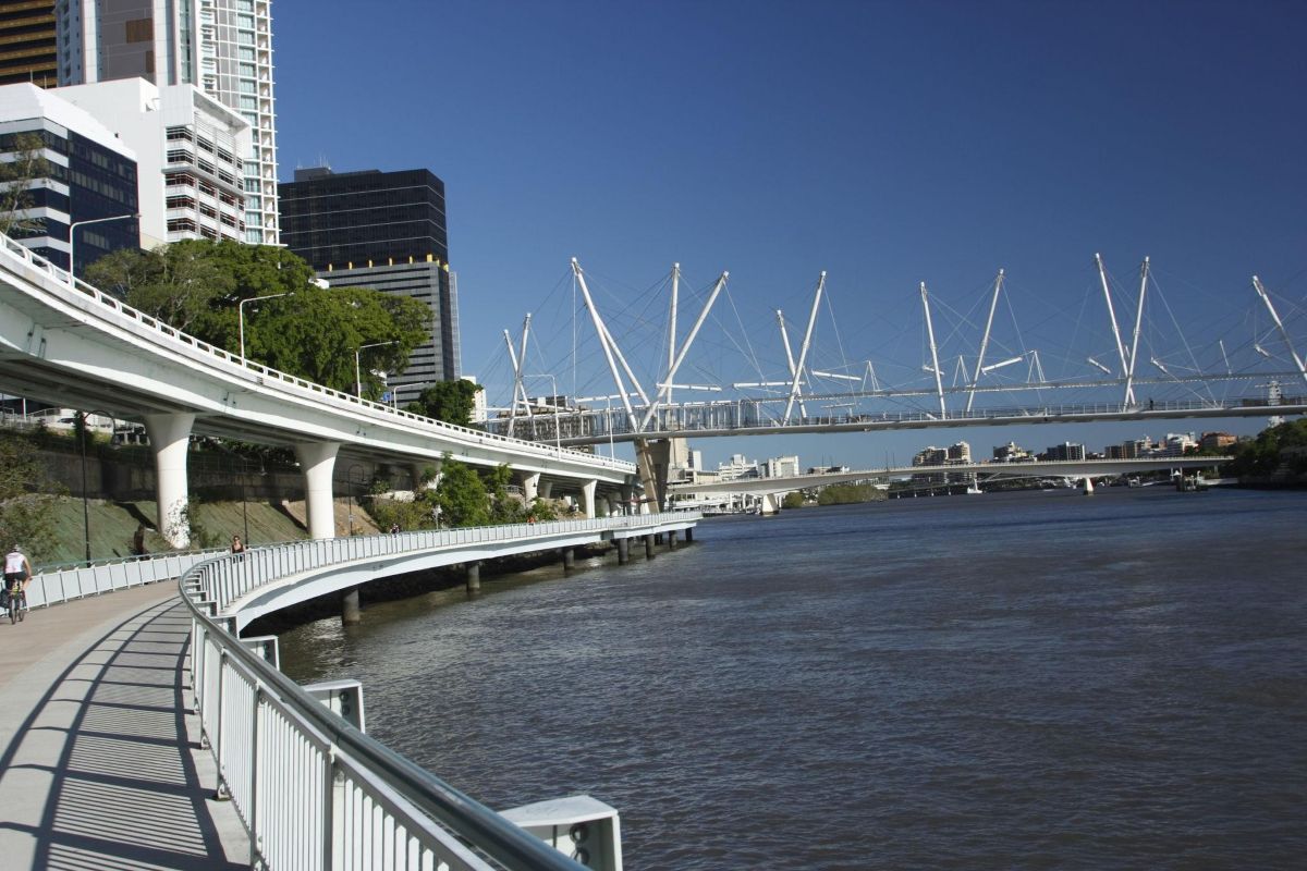 Brisbane riverside promenade with bridge, greenery and city skyline